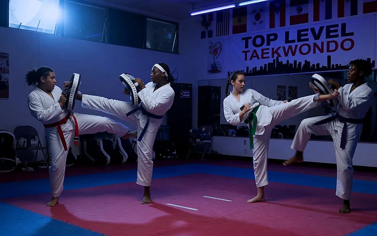 Teen and adult students training with kicking pads